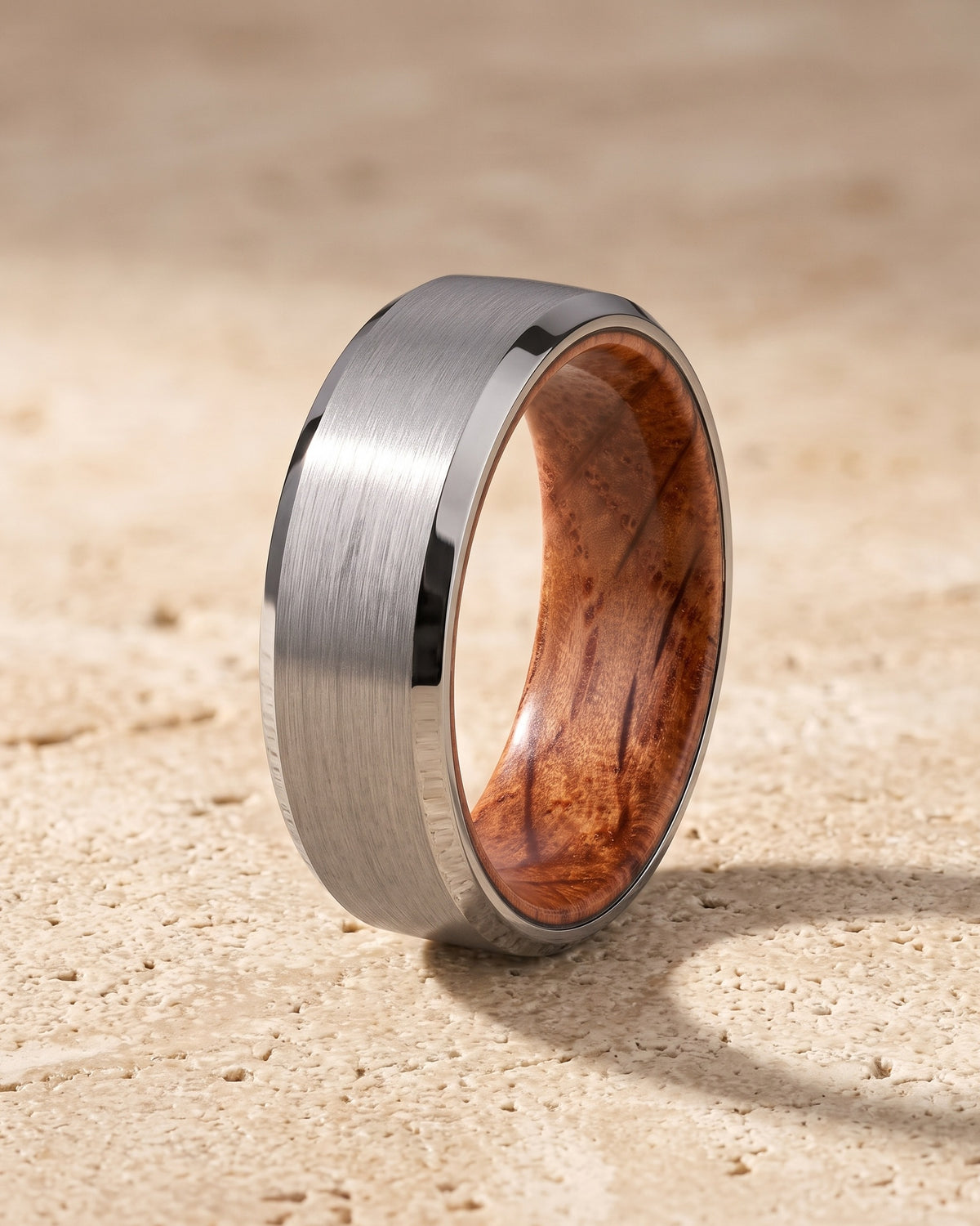 The whole silver-tone Atlas Oak Wood Inlay Ring lying on warm travertine stone