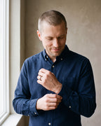 Man in a dark navy cotton oxford shirt by a window wearing the silver-tone Atlas Oak Wood Inlay Ring