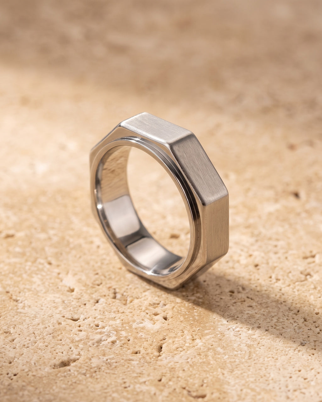 The whole silver-tone Atlas octagon ring lying on warm travertine stone