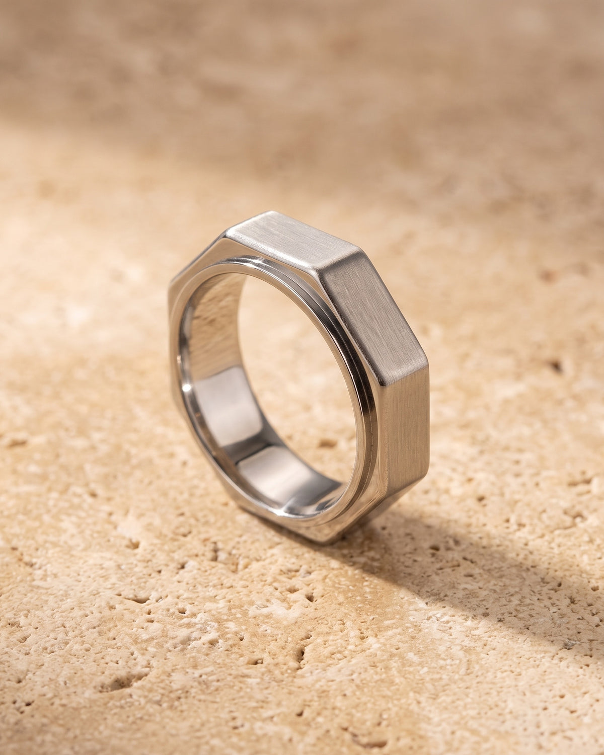 The whole silver-tone Atlas octagon ring lying on warm travertine stone