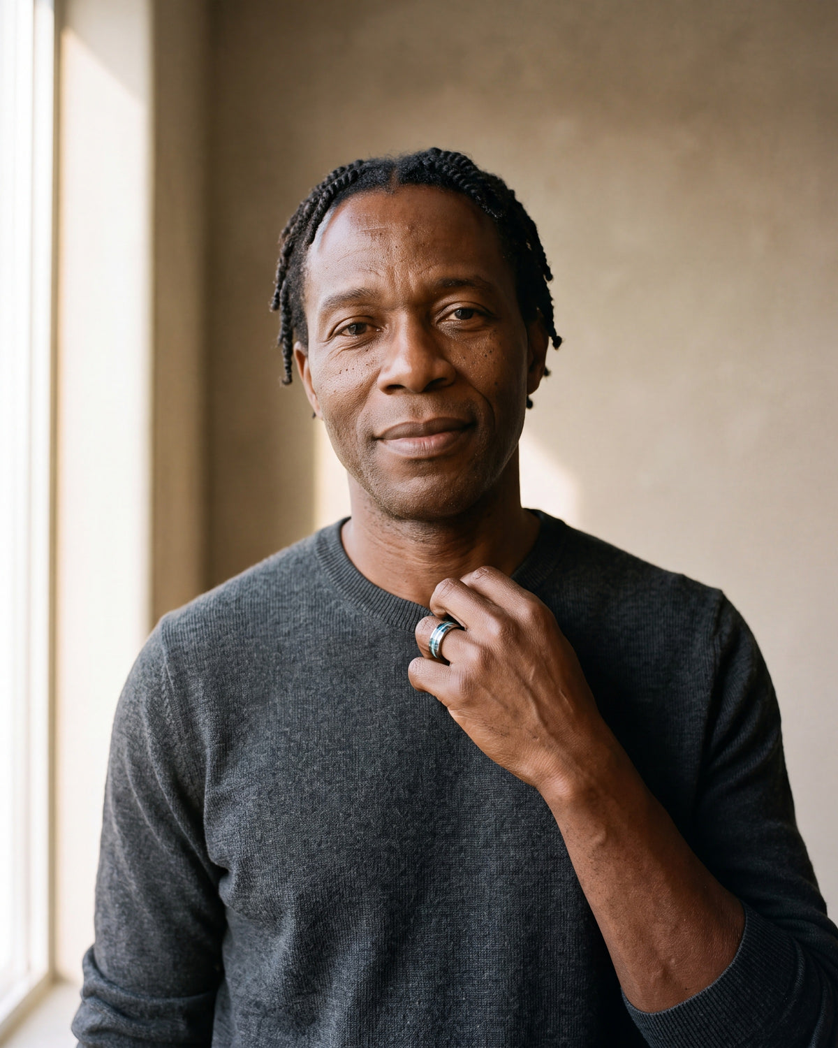 Man in a charcoal fine-gauge knit crew-neck sweater by a window wearing the silver-tone Atlas opal and abalone inlay ring