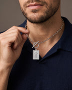 Hand lifting the Atlas Paperclip Chain Cross Necklace at the collarbone