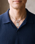 Close-up of the silver Atlas Paperclip Chain Cross Necklace worn by a man, shown at true size