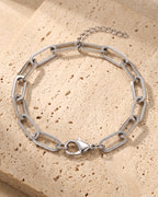The whole silver-tone Atlas Paperclip Link Bracelet lying on warm travertine stone