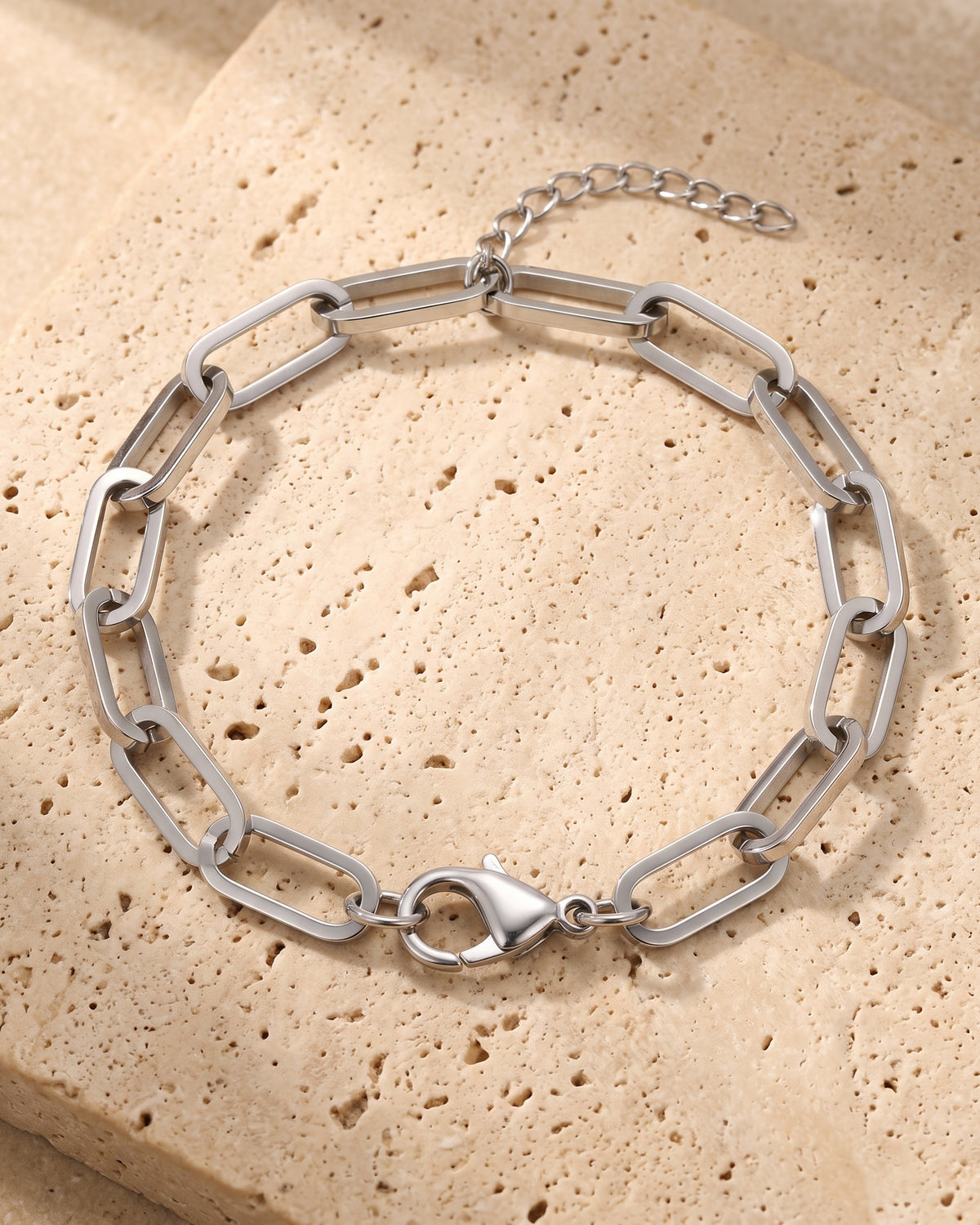 The whole silver-tone Atlas Paperclip Link Bracelet lying on warm travertine stone