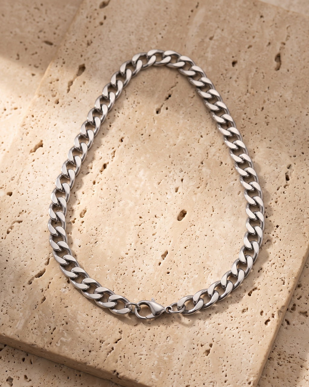 The whole silver-tone Atlas polished curb link chain laid on warm stone