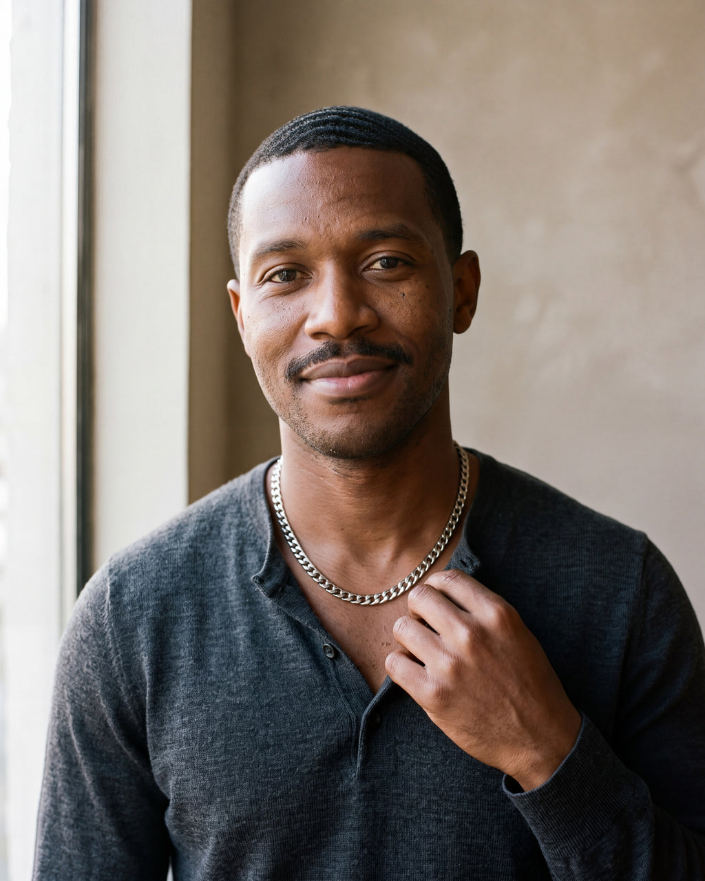 Man in a charcoal henley by a window wearing the silver-tone Atlas polished curb link chain