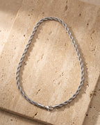 The whole silver-tone Atlas Polished Rope Chain lying on warm travertine stone