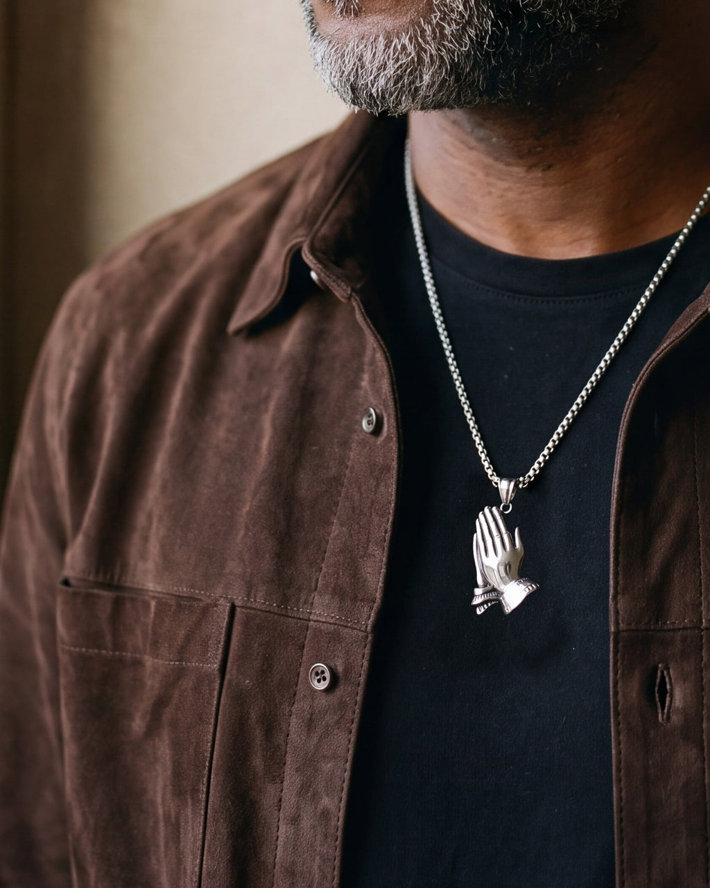 Close-up of the silver-tone Atlas praying hands pendant necklace worn, true size