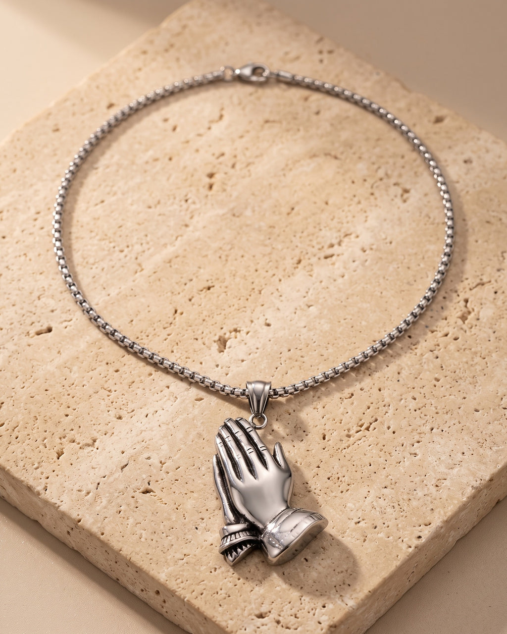 The whole silver Atlas praying hands pendant necklace on warm stone