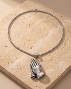 The whole silver Atlas praying hands pendant necklace on warm stone
