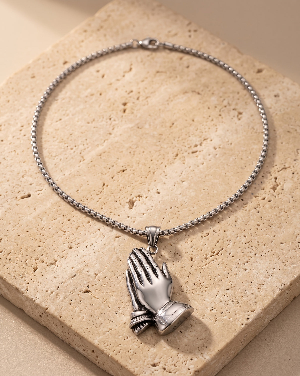 The whole silver Atlas praying hands pendant necklace on warm stone