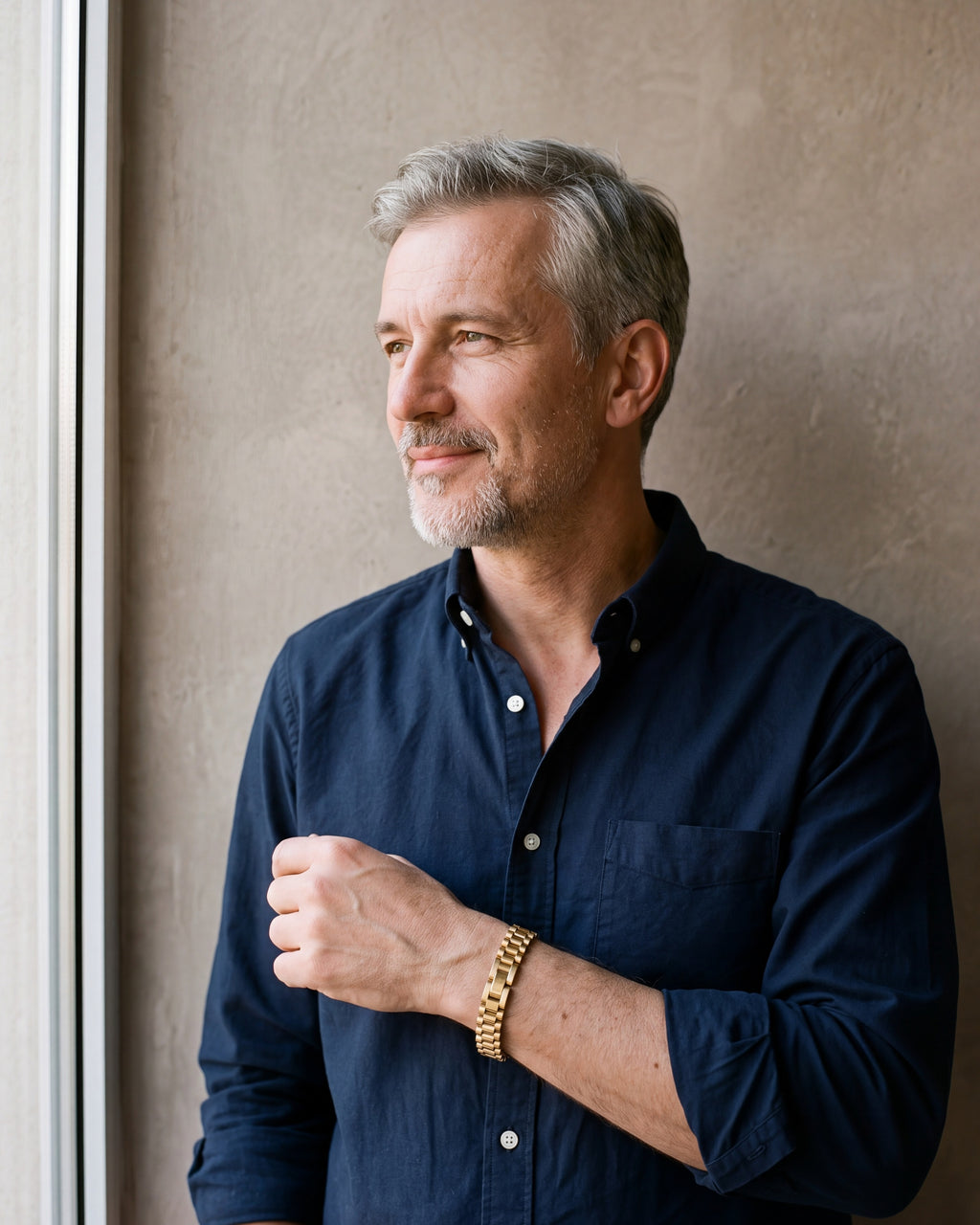 Man in a navy shirt by a window wearing the gold-tone Atlas President link bracelet