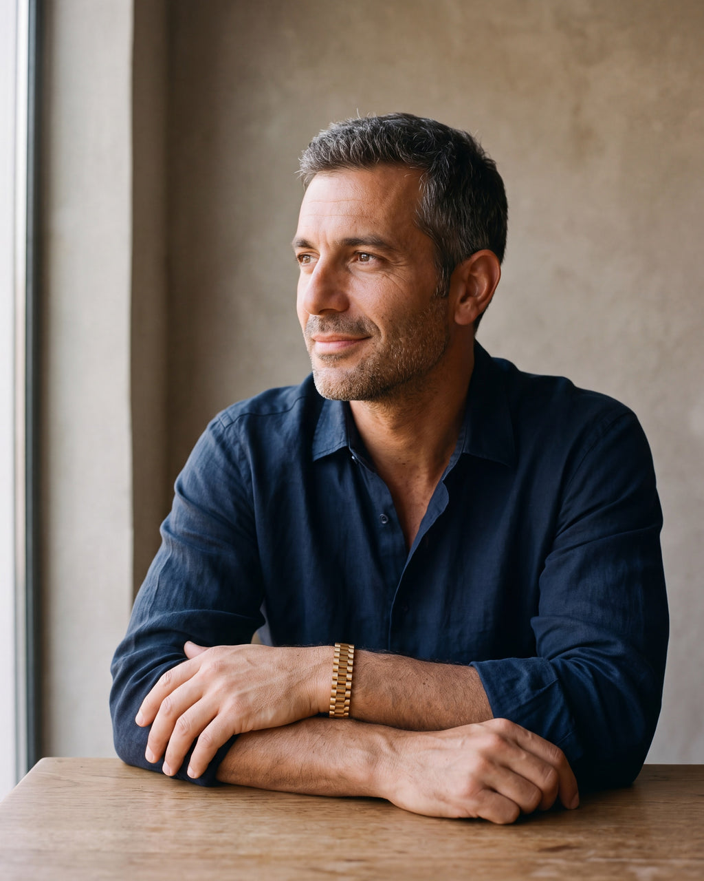 Second man in a dark navy linen shirt wearing the gold-tone Atlas president link bracelet