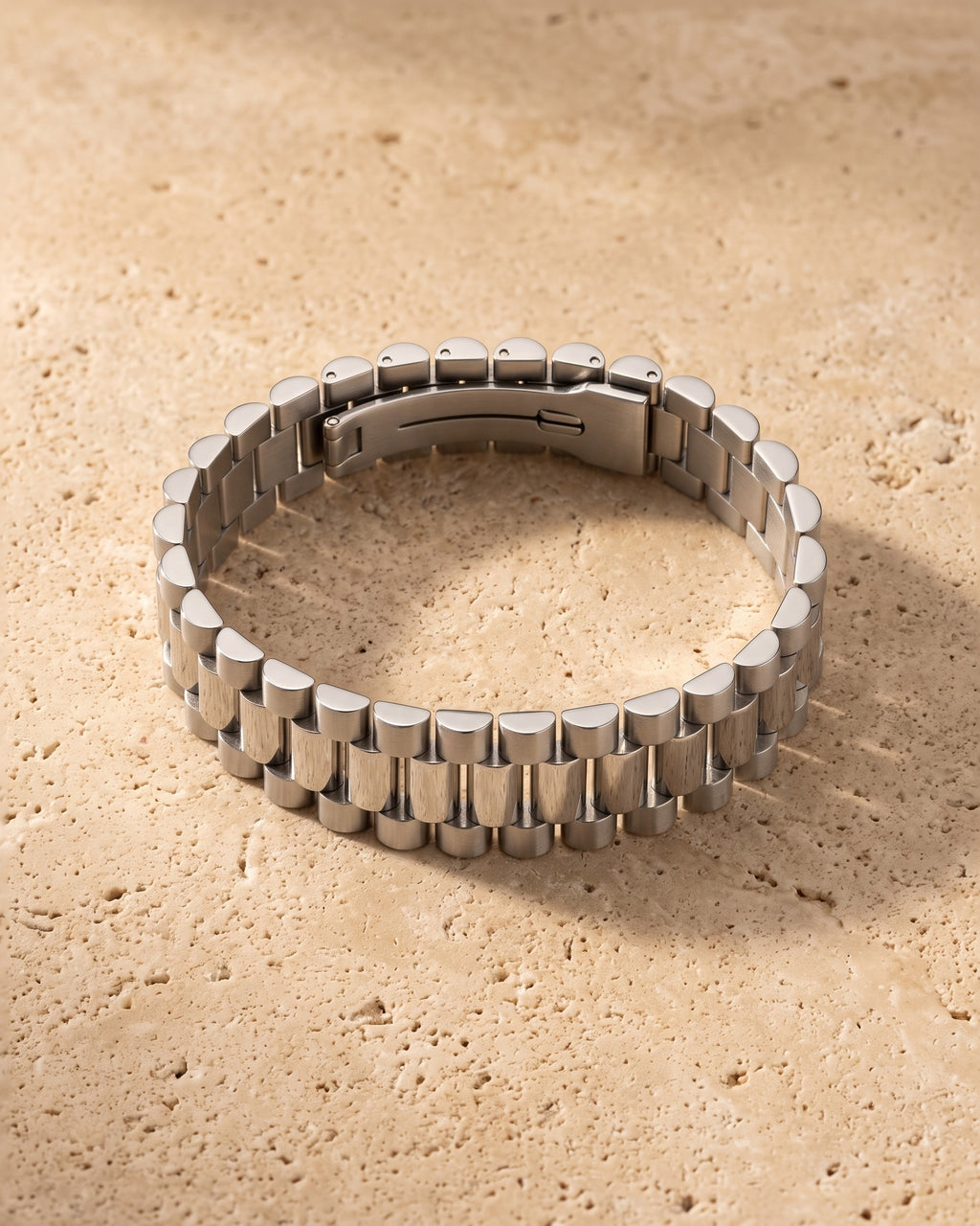 The whole silver-tone Atlas president link bracelet lying on warm travertine stone