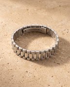 The whole silver-tone Atlas president link bracelet lying on warm travertine stone