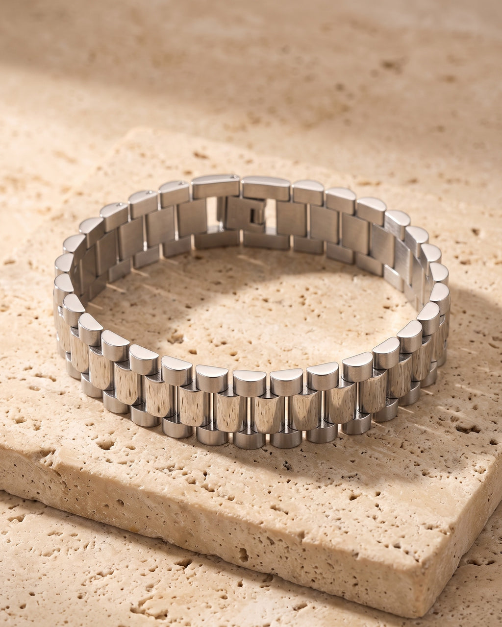 The whole silver-tone Atlas President link bracelet closed on warm stone