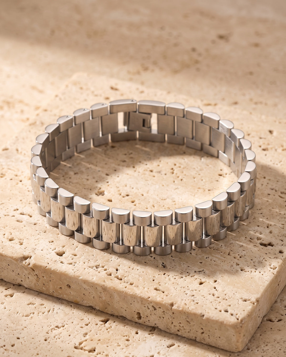 The whole silver-tone Atlas President link bracelet closed on warm stone
