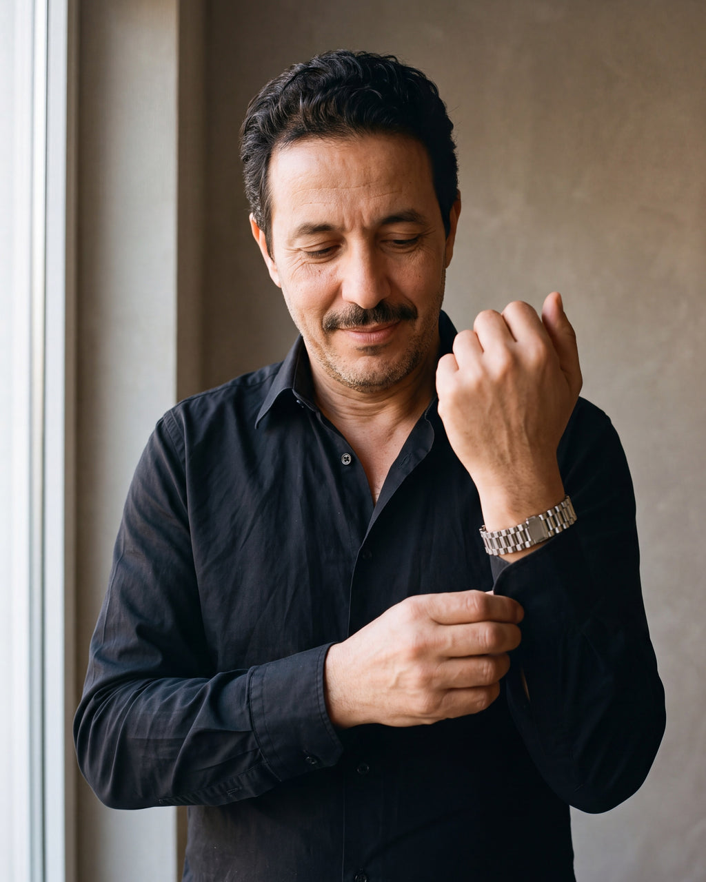 Man in a black shirt adjusting his cuff, wearing the silver-tone Atlas President link bracelet