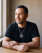 Man in a black T-shirt seated by a window, wearing the Atlas raven Vegvisir compass necklace