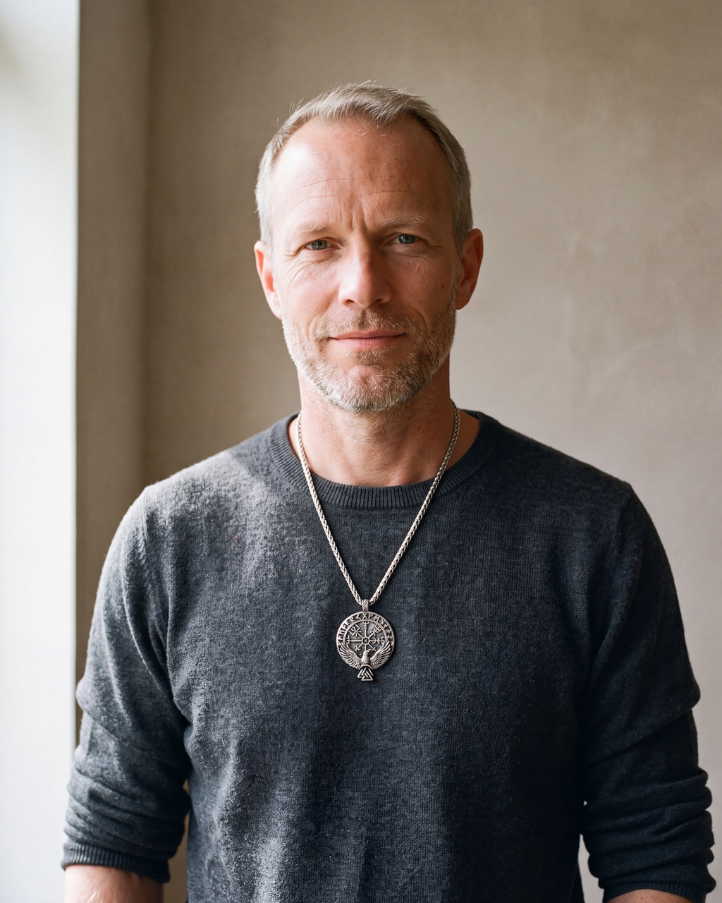 Man in a charcoal knit sweater wearing the Atlas raven Vegvisir compass necklace