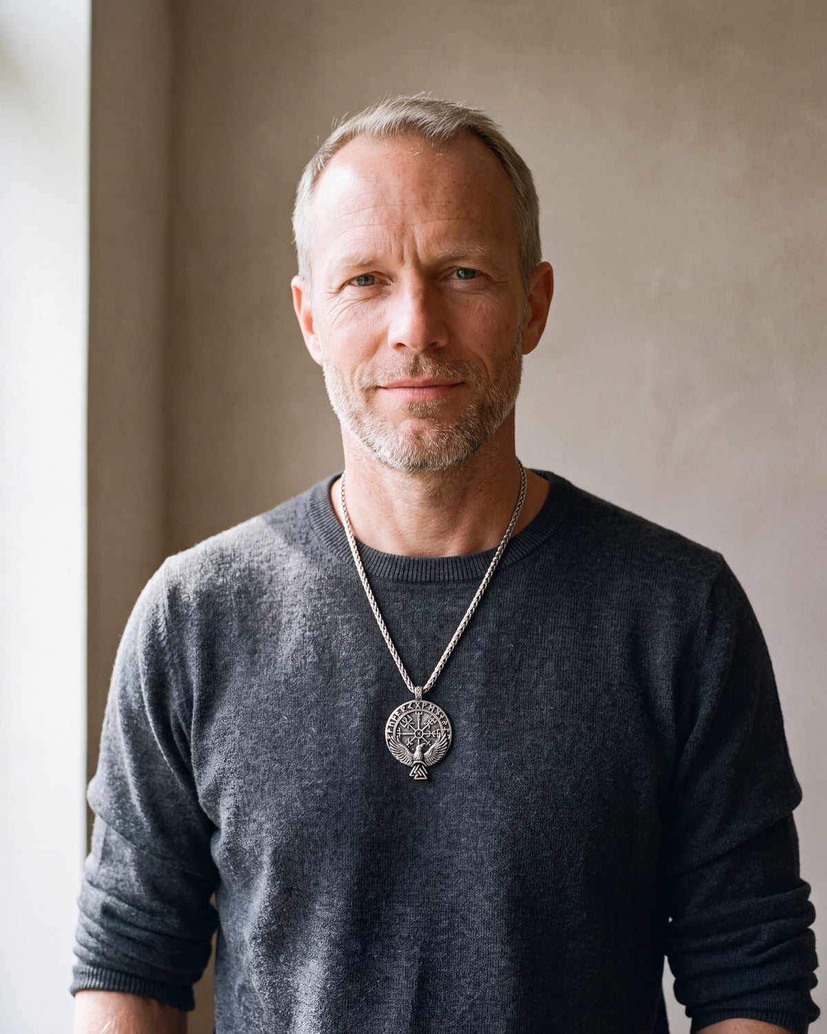 Man in a charcoal knit sweater wearing the Atlas raven Vegvisir compass necklace