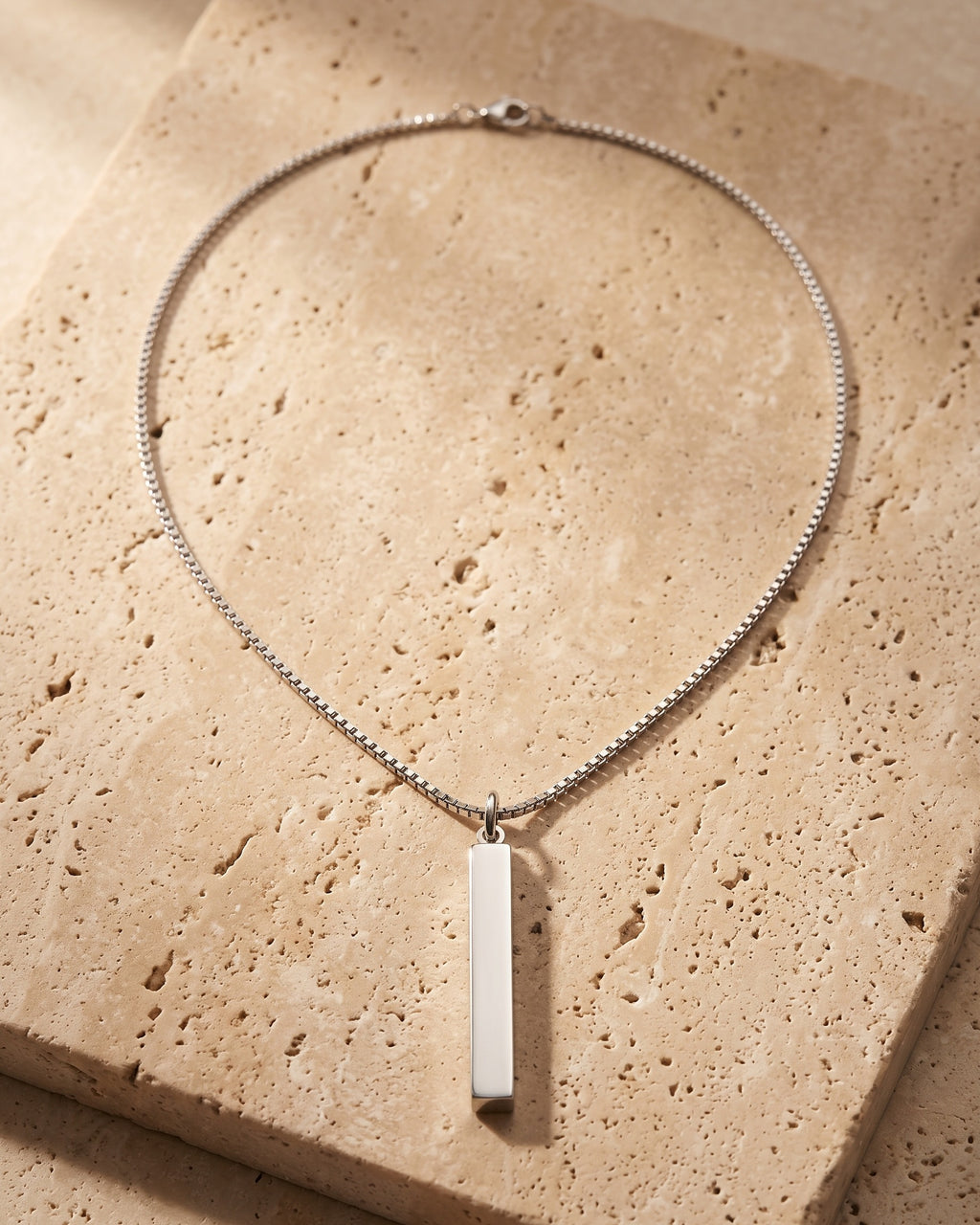 The whole silver-tone Atlas bar pendant necklace on warm stone