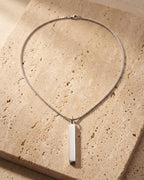The whole silver-tone Atlas bar pendant necklace on warm stone