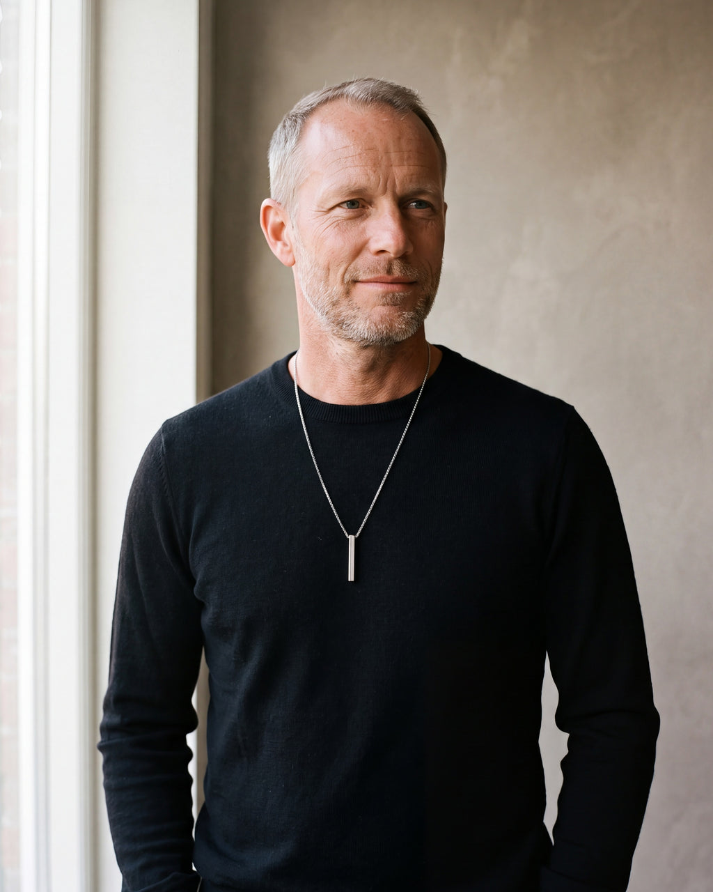 Man in a black sweater wearing the silver-tone Atlas rectangular bar pendant necklace
