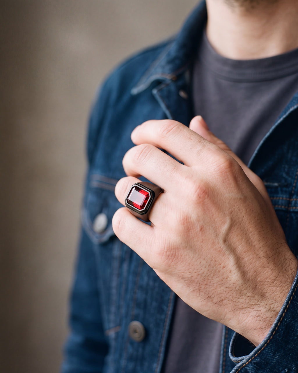 Close-up of the black Atlas red stone signet ring worn by a man, shown at true size