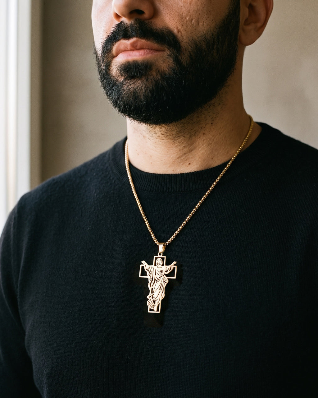 Atlas Risen Christ cross necklace in gold-tone titanium steel worn on the chest, close-up
