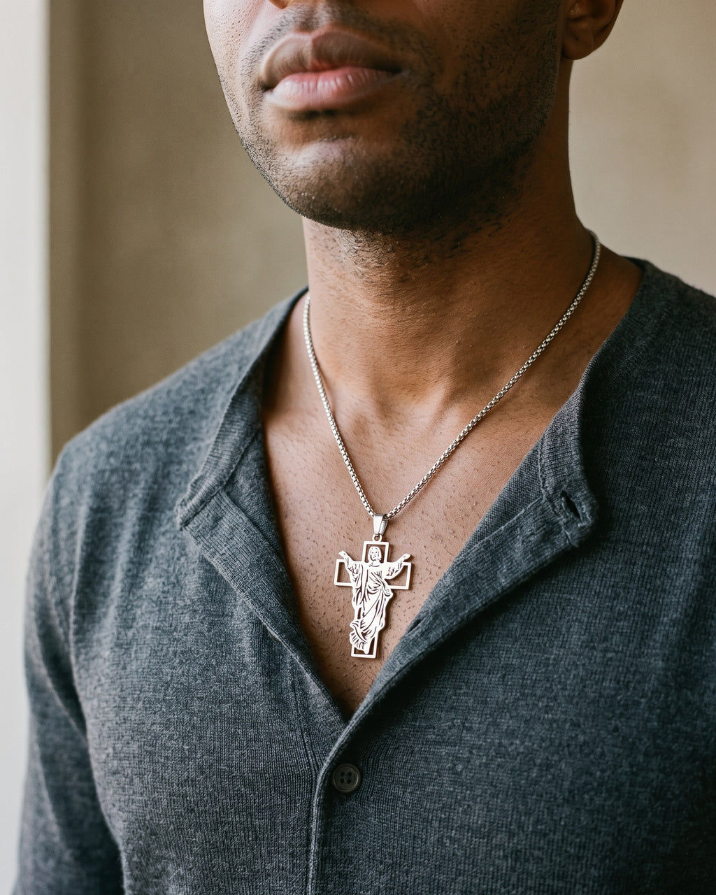 Atlas Risen Christ cross necklace in silver-tone titanium steel worn on the chest, close-up