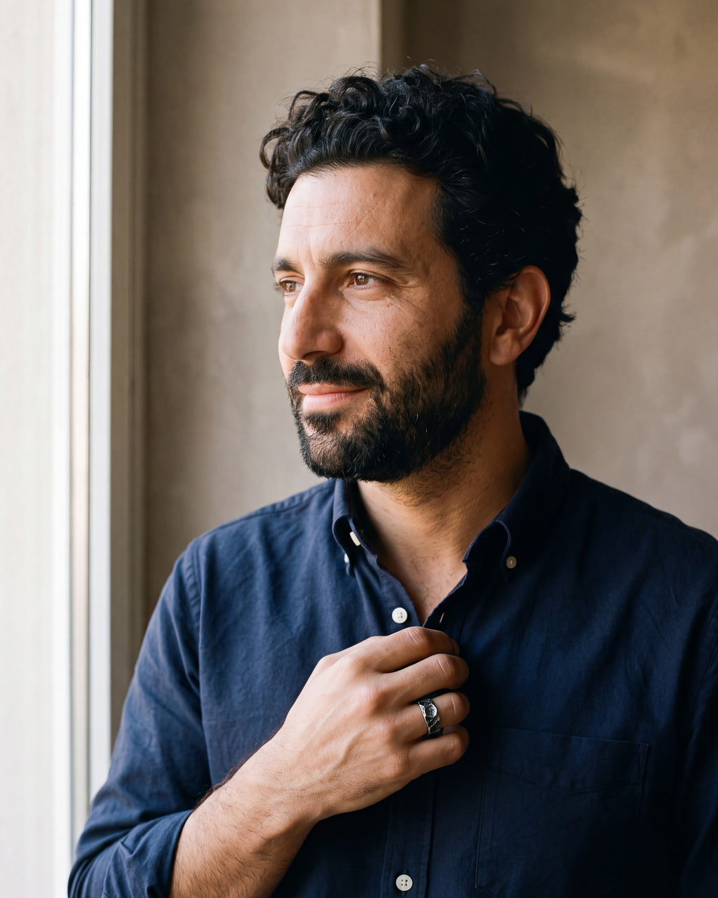 Man in a navy shirt by a window wearing the Atlas rock texture rune ring