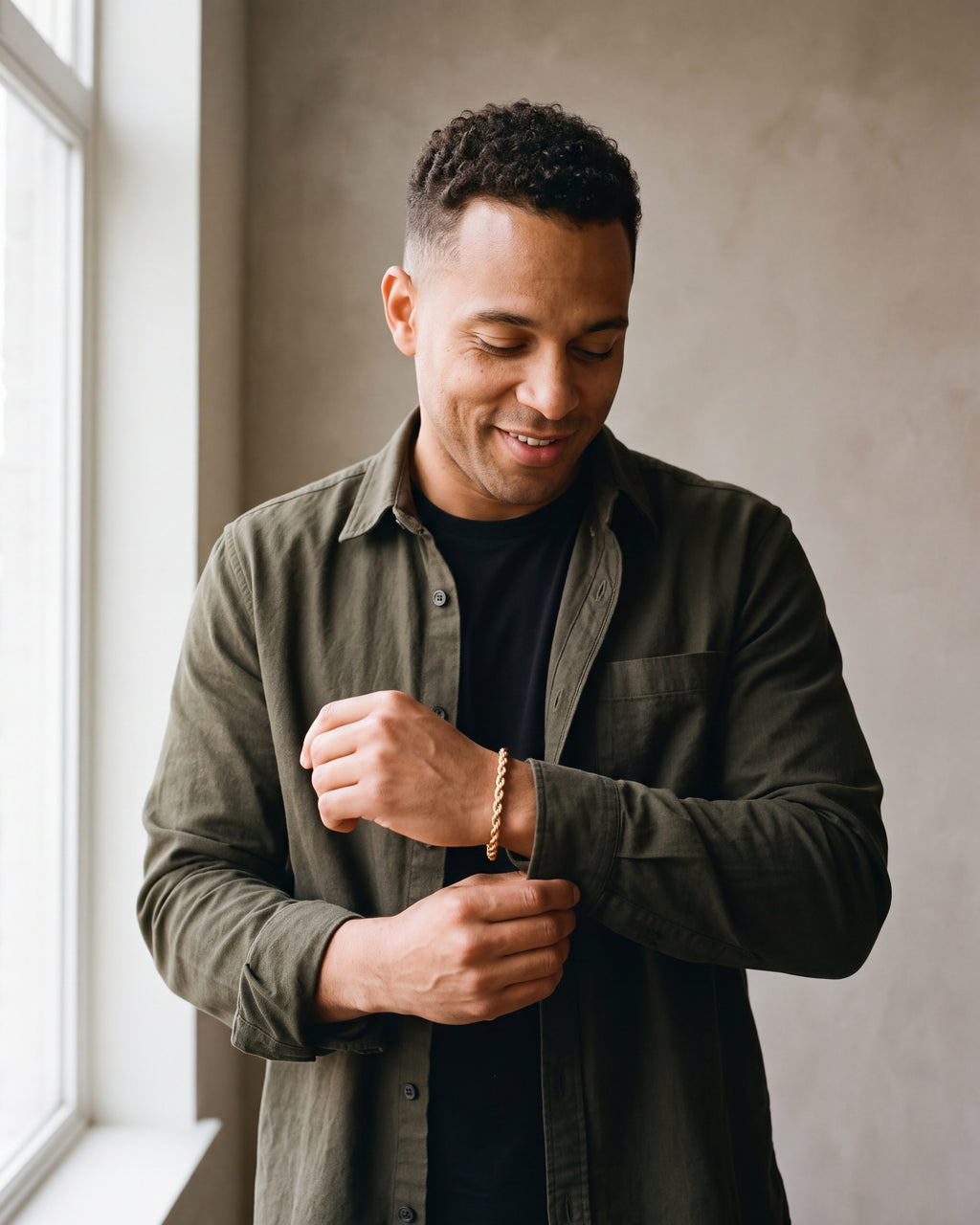 Second man in a dark olive overshirt open over a plain black t-shirt wearing the gold-tone Atlas rope chain bracelet