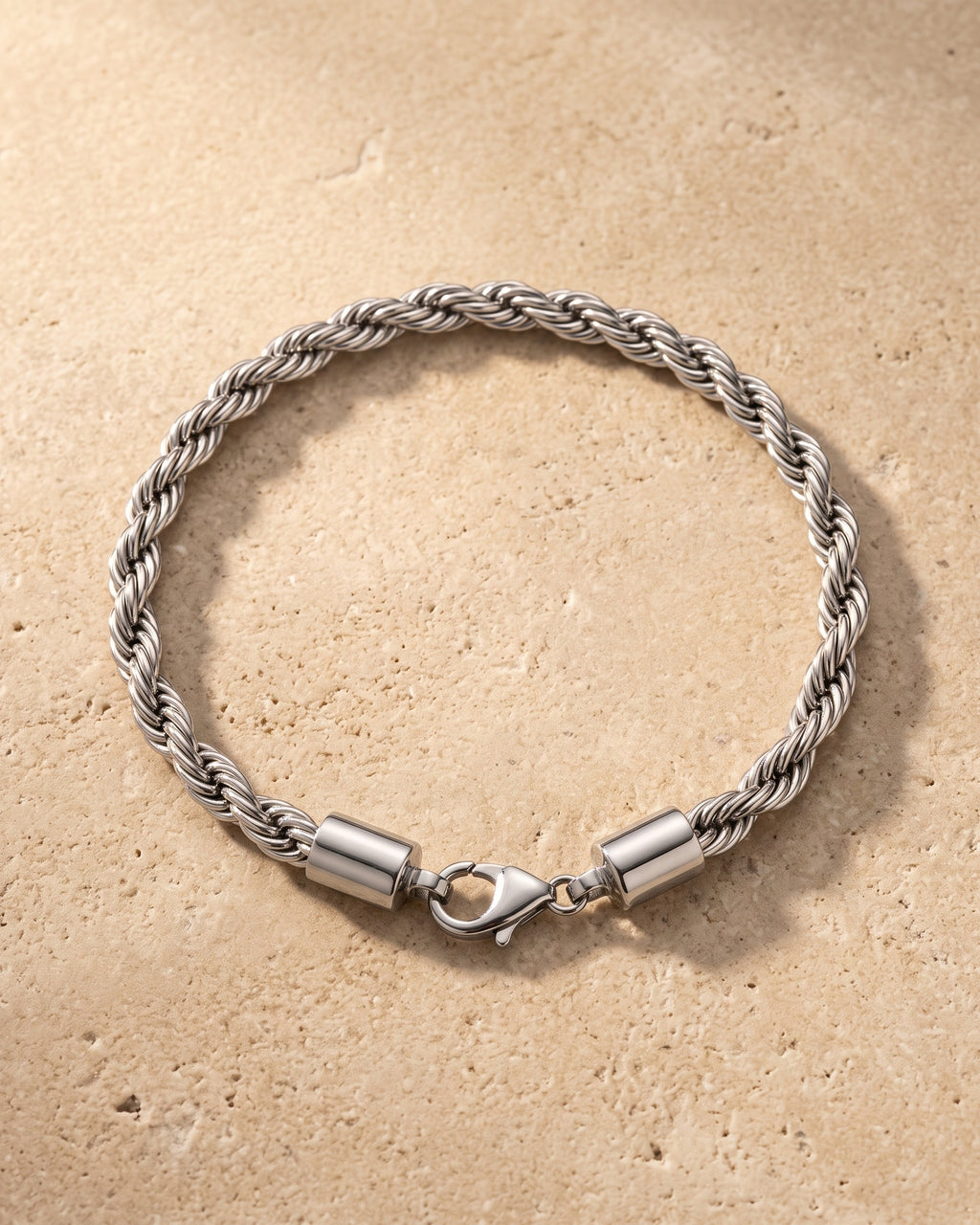 The whole silver Atlas rope chain bracelet lying on warm travertine stone