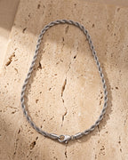 Atlas silver rope chain laid whole on warm stone, lobster clasp closed