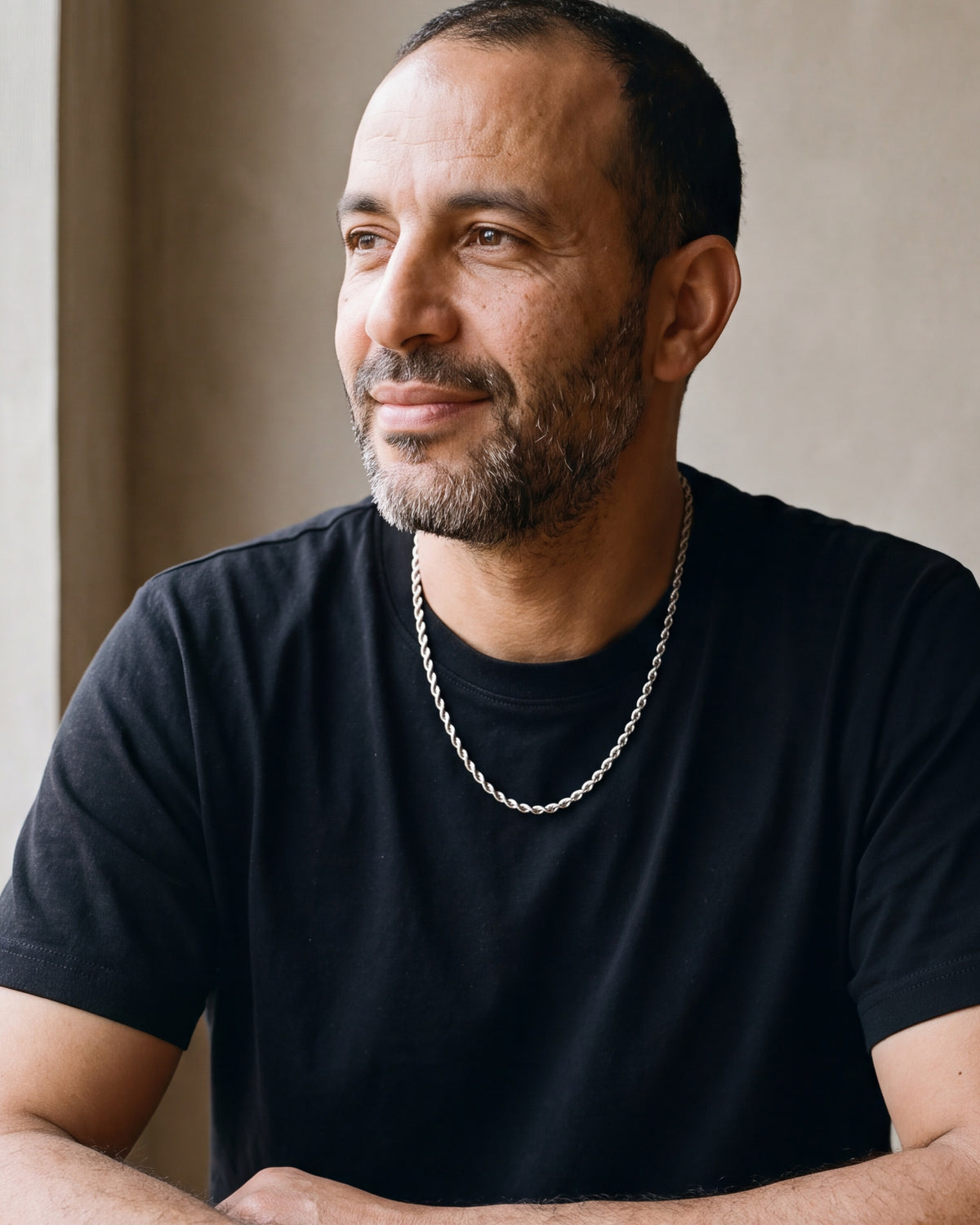 Man in a black t-shirt seated at a wooden table, wearing the 4 mm Atlas rope chain