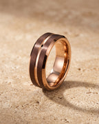 The whole rose gold-tone Atlas Rose Gold-Tone Groove Ring lying on warm travertine stone
