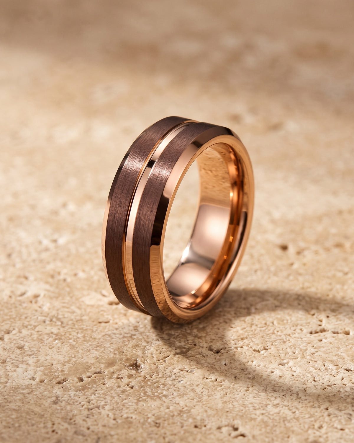 The whole rose gold-tone Atlas Rose Gold-Tone Groove Ring lying on warm travertine stone