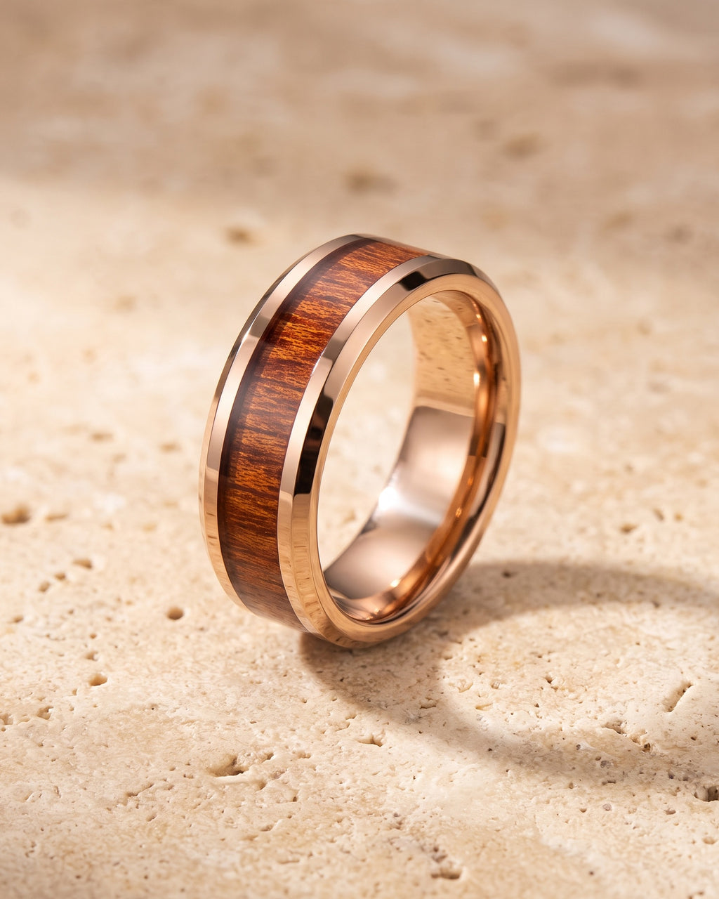 The Atlas rose gold-tone wood inlay tungsten ring standing on warm stone
