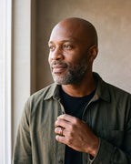 Man in an olive overshirt by a window wearing the Atlas wood inlay tungsten ring