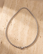 The whole silver Atlas round box chain laid on warm stone, lobster clasp closed