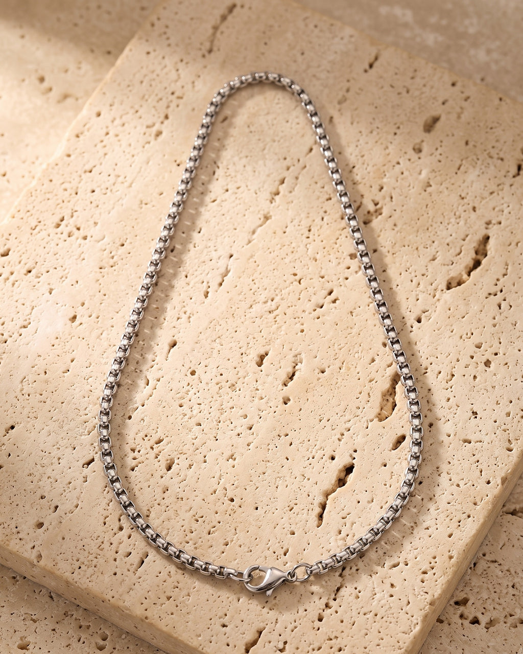 The whole silver-tone Atlas rounded box chain on warm stone, lobster clasp