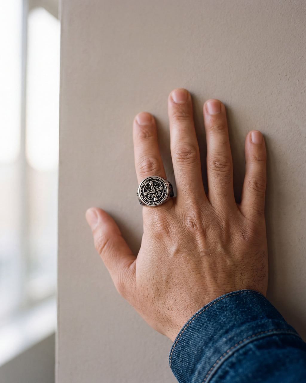 Close-up of the antiqued silver Atlas Saint Benedict signet ring worn by a man, shown at true size