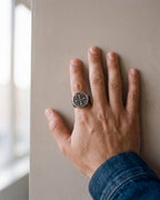 Close-up of the antiqued silver Atlas Saint Benedict signet ring worn by a man, shown at true size