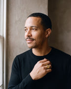 Man in a black merino sweater by a window wearing the gold-tone Atlas Saint Benedict signet ring
