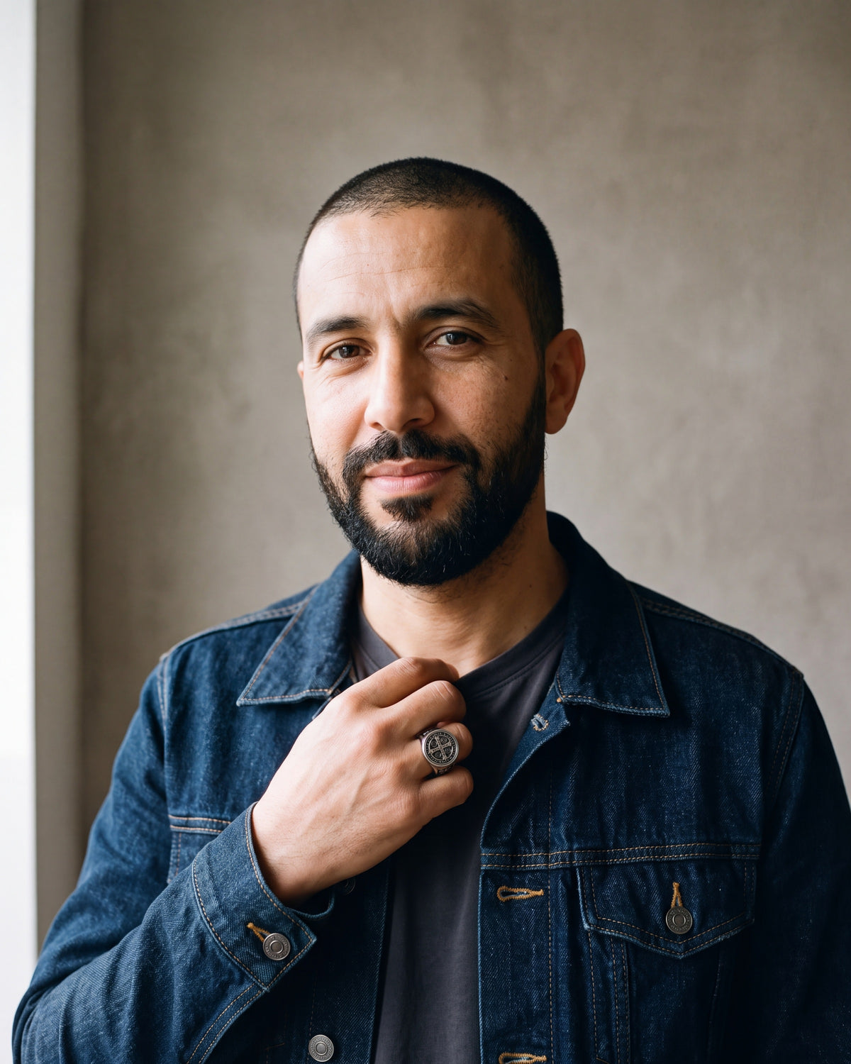Man in a denim jacket by a window wearing the antiqued silver Atlas Saint Benedict signet ring