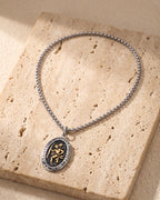 The whole silver-tone Atlas Saint Christopher oval pendant necklace laid on warm stone
