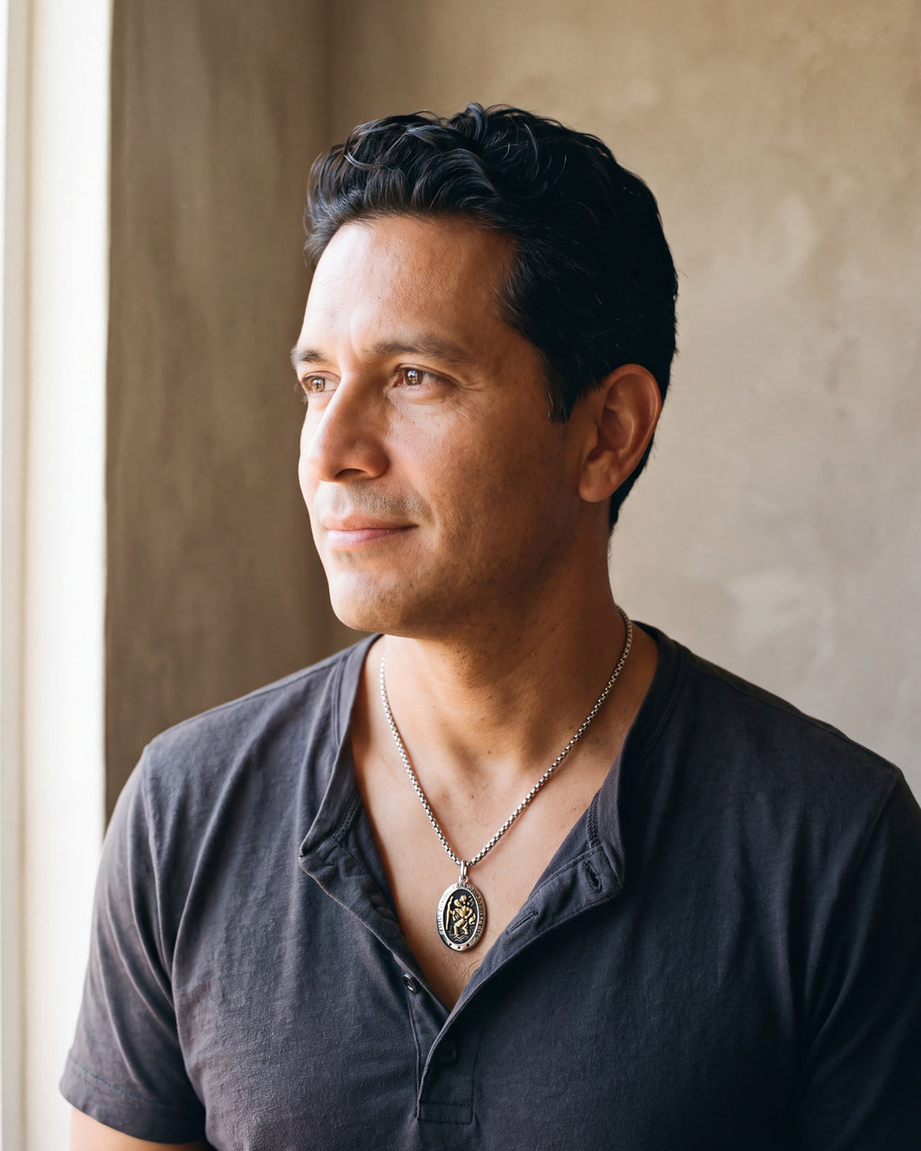 Man in a charcoal henley seen in profile wearing the silver-tone Atlas Saint Christopher oval pendant necklace