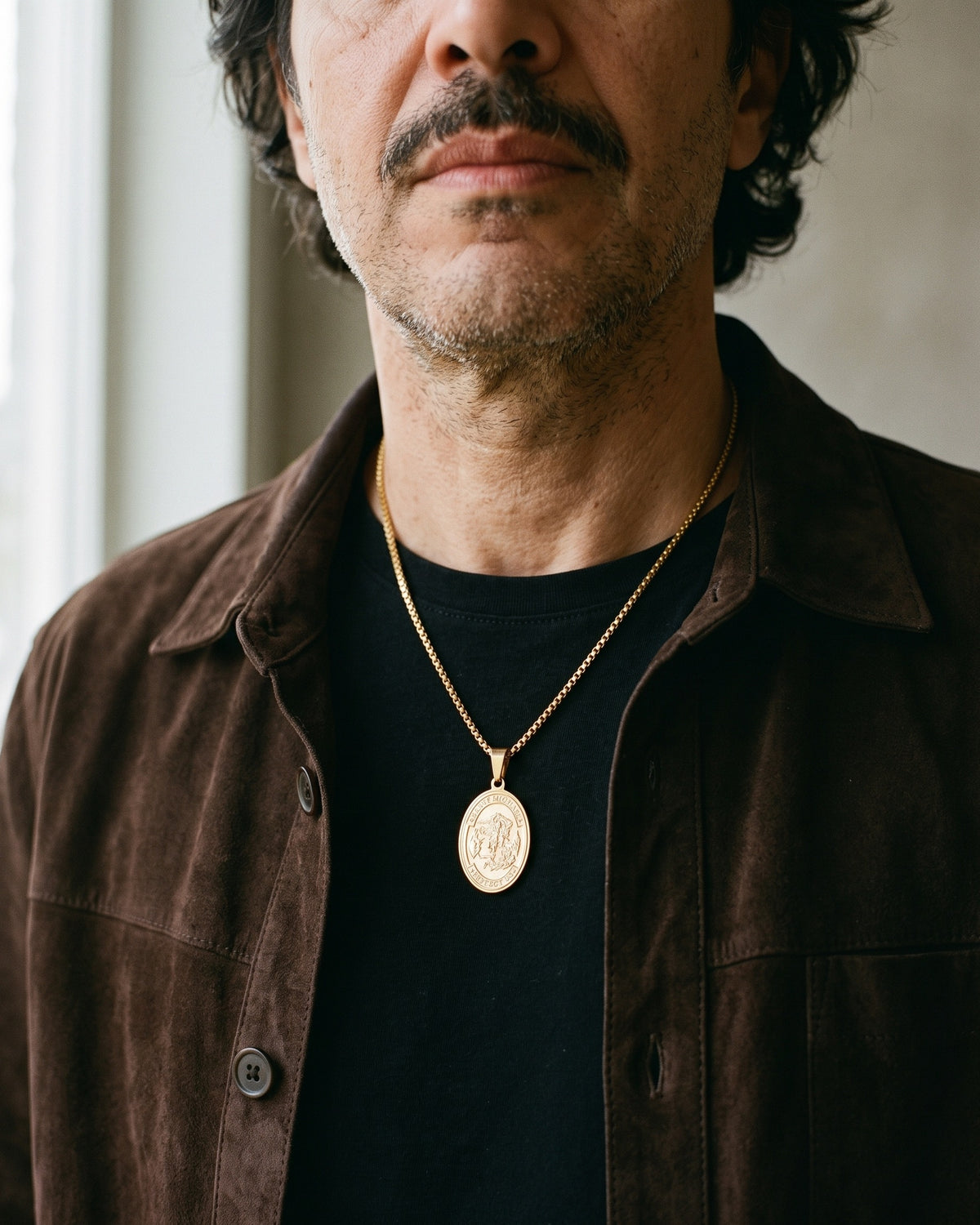 Atlas Saint Michael oval pendant necklace in gold-tone titanium steel worn on the chest, close-up